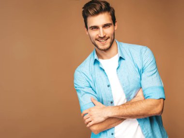 Portre yakışıklı gülümseyen şık hipster lumbersexual işadamı modeli mavi gömlek elbise giymiş. Altın arka plan üzerinde poz moda adam. Çapraz kollar