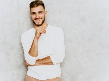 Yakışıklı gülümseyen hipster lumbersexual işadamı modeli rahat yaz beyaz elbise giyen portresi. Moda şık adam gri duvara poz