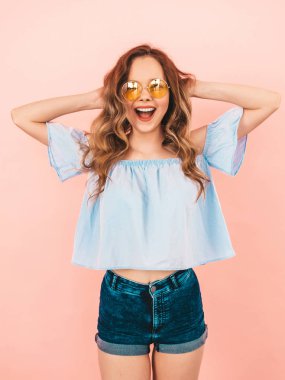 Yuvarlak güneş gözlüğü güzel gülümseyen şirin model portresi. Yaz hipster renkli giysileri kızı. Model pembe arka plan poz. Saçları ile oynamak