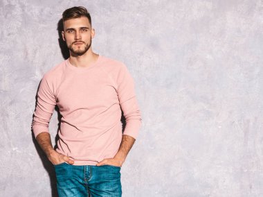 Portre yakışıklı gülümseyen hipster lumbersexual işadamı modeli rahat yaz pembe elbise giyiyor. Moda şık adam gri duvara poz