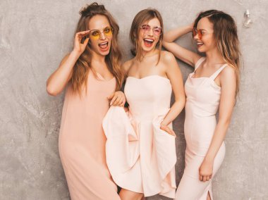 Üç genç güzel gülümseyen hippi kız trendy yaz ışık elbiseler pembe. Seksi kaygısız kadın gri duvara yakın poz. Pozitif eğleniyor yuvarlak güneş gözlüğü modellerinde