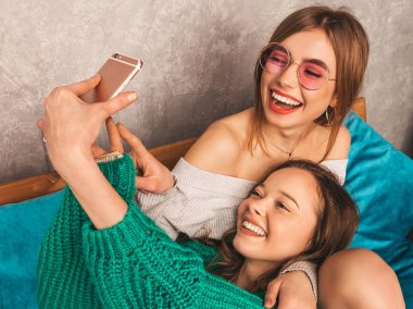 İki genç gülümseyen güzel kızlar trendy yaz hipster giysileri güzel. Seksi kaygısız kadın iç ve alma selfie poz. Olumlu modelleri smartphone ile eğleniyor