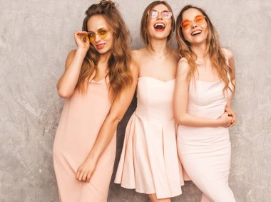 Üç genç güzel gülümseyen hippi kız trendy yaz ışık elbiseler pembe. Seksi kaygısız kadın gri duvara yakın poz. Pozitif eğleniyor yuvarlak güneş gözlüğü modellerinde