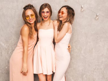 Üç genç güzel gülümseyen hippi kız trendy yaz ışık elbiseler pembe. Seksi kaygısız kadın gri duvara yakın poz. Pozitif eğleniyor yuvarlak güneş gözlüğü modellerinde