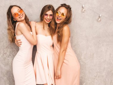 Üç genç güzel gülümseyen hippi kız trendy yaz ışık elbiseler pembe. Seksi kaygısız kadın gri duvara yakın poz. Pozitif eğleniyor yuvarlak güneş gözlüğü modellerinde