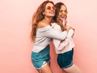 İki genç güzel gülümseyen hippi kız trendy yaz hipster giysileri. Seksi kaygısız kadınlar, pembe arka plan poz. Olumlu modelleri eğleniyor