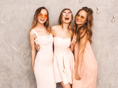 Üç genç güzel gülümseyen hippi kız trendy yaz ışık elbiseler pembe. Seksi kaygısız kadın gri duvara yakın poz. Pozitif eğleniyor yuvarlak güneş gözlüğü modellerinde