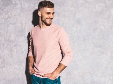 Portre yakışıklı gülümseyen hipster lumbersexual işadamı modeli rahat yaz pembe elbise giyiyor. Moda şık adam gri duvara poz