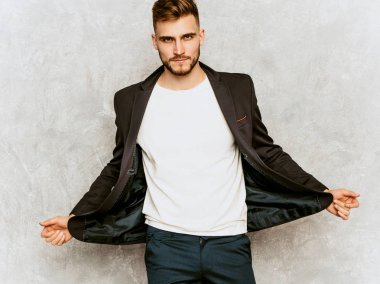 Yakışıklı ciddi hipster lumbersexual işadamı modeli giyiyor rahat siyah takım portresi. Moda şık adam gri duvara poz