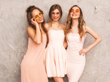 Üç genç güzel gülümseyen hippi kız trendy yaz ışık elbiseler pembe. Seksi kaygısız kadın gri duvara yakın poz. Pozitif eğleniyor yuvarlak güneş gözlüğü modellerinde
