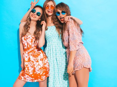 Üç genç güzel gülümseyen hippi kız trendy yaz renkli elbiseler. Mavi izole güneş gözlüklü seksi kaygısız kadın. Delirmek olumlu modelleri