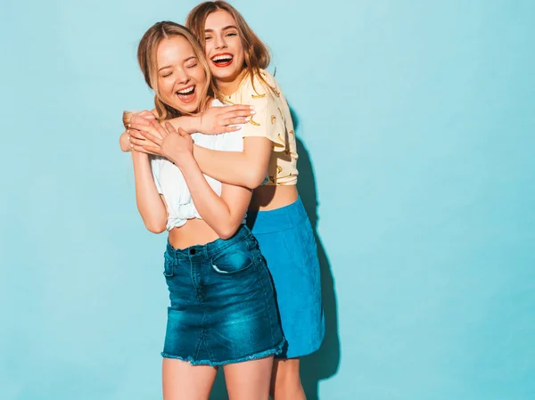 两个年轻美丽的微笑的金发嬉皮士女孩在时尚夏天五颜六色的 T恤衣服 性感无忧无虑的女人摆在蓝色的墙壁附近 积极的模型有乐趣和拥抱 — 图库照片