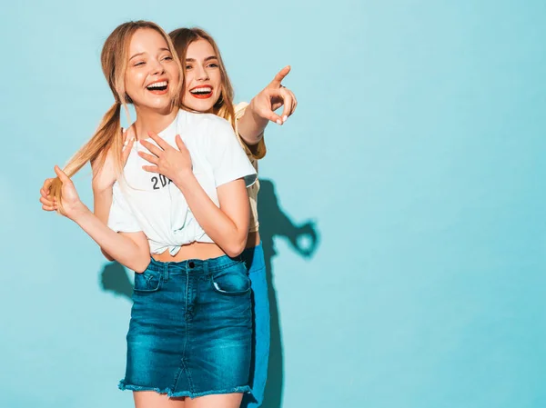 两个年轻美丽的微笑的金发嬉皮士女孩在时尚夏天五颜六色的 T恤衣服 性感无忧无虑的女人摆在蓝色的墙壁附近 以店铺销售为重点的积极模式 — 图库照片