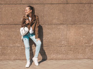 Yaz hipster ceket giysiler giymiş güzel gülümseyen esmer model portresi. Duvara yakın sokakta poz veren modaya uygun kız. Yuvarlak güneş gözlüğü komik ve pozitif kadın. Tam uzunlukta