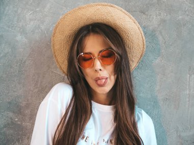 Kameraya bakan genç güzel gülümseyen kadın Closeup portraif. Rahat yazlık giysiler ve şapka trendy kız. Pozitif kadın komik yüz yapma ve dil gösteren