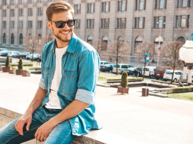 Yakışıklı gülümseyen şık hipster lumbersexual işadamı modeli portresi. Kot pantolon ceketi giymiş bir adam. Moda erkek güneş gözlüğü sokak arka planda poz