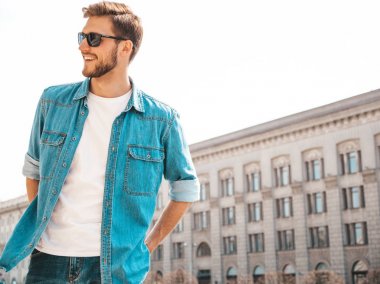 Yakışıklı gülümseyen şık hipster lumbersexual işadamı modeli portresi. Kot pantolon ceketi giymiş bir adam. Moda erkek güneş gözlüğü sokak arka planda poz