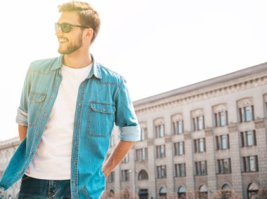 Yakışıklı gülümseyen şık hipster lumbersexual işadamı modeli portresi. Kot pantolon ceketi giymiş bir adam. Moda erkek güneş gözlüğü sokak arka planda poz
