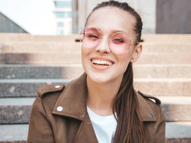 Yaz hipster ceket giysiler giymiş güzel gülümseyen esmer model portresi. Sokak arka planda poz veren modaya uygun bir kız. Yuvarlak güneş gözlüğü komik ve pozitif kadın