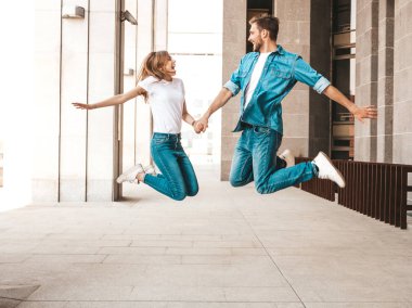 Rahat yazlık giysiler içinde gülümseyen güzel kız ve onun yakışıklı erkek arkadaşı Portresi. Mutlu neşeli aile atlama ve sokak arka planda eğlenmek. Delirmek