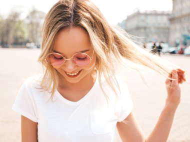 Yaz hipster giysileri giymiş güzel gülümseyen sarışın model portresi. Yuvarlak güneş gözlüğü sokak arka planda poz Trendy kız. Komik ve pozitif kadın eğleniyor