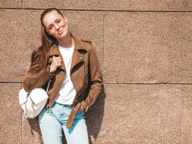 Yaz hipster ceket ve kot elbise giymiş güzel gülümseyen esmer model Portresi. Duvara yakın sokakta poz veren modaya uygun kız. Yuvarlak güneş gözlüğü komik ve pozitif kadın