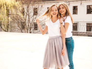 Moda yaz beyaz t-shirt giysiler iki genç güzel sarışın gülümseyen hipster kız Portresi. Seksi kaygısız kadınlar sokak arka planda poz. Olumlu modeller eğleniyor. Sarılma