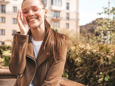 Yaz hipster ceket giysiler giymiş güzel gülümseyen esmer model portresi. Sokak arka planda poz veren modaya uygun bir kız. Yuvarlak güneş gözlüğü komik ve pozitif kadın