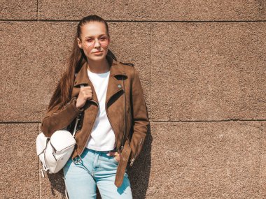 Yaz hipster ceket ve kot elbise giymiş güzel esmer model Portresi. Duvara yakın sokakta poz veren modaya uygun kız. Yuvarlak güneş gözlüğü komik ve pozitif kadın