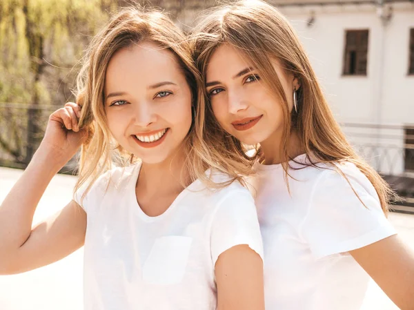 两个年轻美丽的金发微笑的嬉皮士女孩在时髦的夏季白色T恤衣服的肖像 性感的无忧无虑的女人在街头背景摆姿势 积极模型有乐趣 — 图库照片