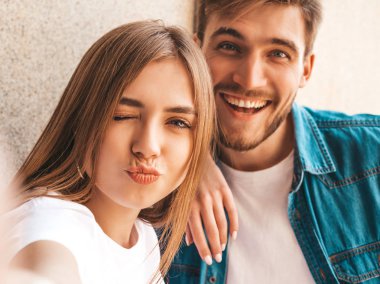Gülümseyen güzel kız ve rahat yazlık giysiler onun yakışıklı erkek arkadaşı. Mutlu aile akıllı telefon kamerasında selfie selfie kendi portresini çekiyor. Eğlenmek ve ördek surat yapmak