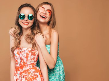 Trendy yaz renkli elbiseler iki genç güzel gülümseyen hipster kız. Altın arka planda poz veren seksi kaygısız kadınlar. Pozitif modeller güneş gözlüğü deli gidiyor