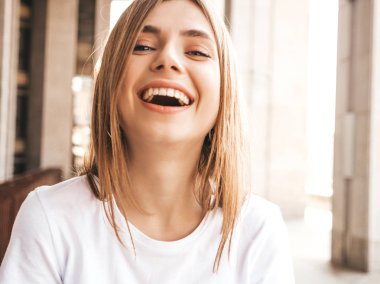 Yaz hipster giysileri giymiş güzel gülümseyen sarışın model portresi. Sokak arka planda poz veren modaya uygun bir kız. Komik ve pozitif kadın eğleniyor