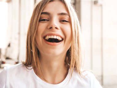 Yaz hipster giysileri giymiş güzel gülümseyen sarışın model portresi. Sokak arka planda poz veren modaya uygun bir kız. Komik ve pozitif kadın eğleniyor