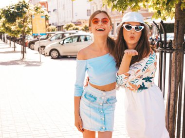 Trendy yazlık giysiler ve panama şapka iki genç güzel gülümseyen hipster kız. Seksi kaygısız kadınlar sokak arka planda poz. Güneş gözlüğü ile eğlenen pozitif modeller. Sarılma