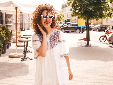 Yaz hipster beyaz elbise giymiş afro bukleler saç modeli ile güzel gülümseyen model. Seksi kaygısız kız sokakta poz. Trendy komik ve pozitif kadın güneş gözlüğü eğlenmek. Dili gösterir