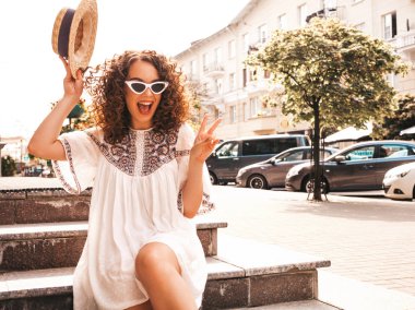 Yaz hipster beyaz elbise giymiş afro bukleler saç modeli ile güzel gülümseyen model. Seksi kaygısız kız sokakta poz. Trendy ve pozitif kadın güneş gözlüğü eğlenmek. Şapkalı