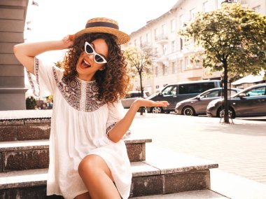 Yaz hipster beyaz elbise giymiş afro bukleler saç modeli ile güzel gülümseyen model. Seksi kaygısız kız sokakta poz. Trendy ve pozitif kadın güneş gözlüğü eğlenmek. Şapkalı