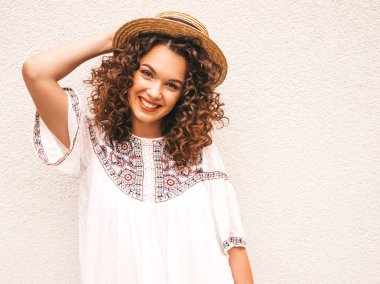 Yaz hipster beyaz elbise giymiş afro bukleler saç modeli ile güzel gülümseyen model. Seksi kaygısız kız şapka beyaz duvar yakınında sokakta poz. Komik, pozitif kadın eğleniyor ve delioluyor
