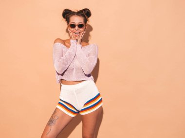 İki boynuzları saç modeli ile genç güzel seksi kadın Portresi. Rahat yaz hipster örgü hırka konu moda kız, güneş gözlüğü şort. Yüzüne yakın elleri ile şok ve şaşırttı