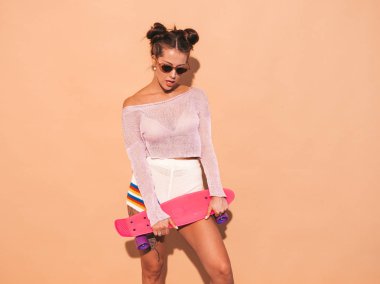 Güneş gözlüğü genç güzel seksi gülümseyen hipster kadın. Yaz aylarında trendy kız örgü hırka konu, şort. Pozitif kadın pembe kuruş kaykay ile deli gidiyor, izole