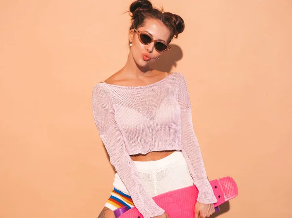 年轻美丽性感微笑的时髦女人在太阳镜 时髦的女孩在夏天针织开衫主题 积极女性去疯狂与粉红色便士滑板 孤立上 — 图库照片