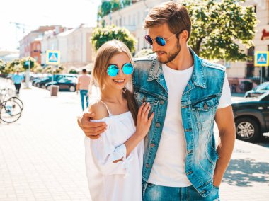 Gülümseyen güzel kız ve onun yakışıklı erkek arkadaşı sokakta yürüyor. Rahat yazlık elbiseli kadın ve kot pantolon giyen bir erkek. Mutlu neşeli çift aile güneş gözlüğü eğlenmek