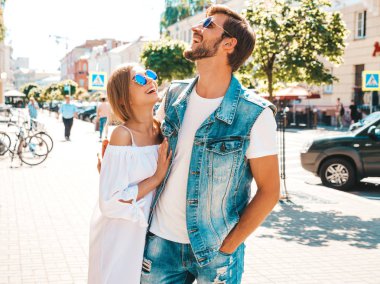 Gülümseyen güzel kız ve onun yakışıklı erkek arkadaşı sokakta yürüyor. Rahat yazlık elbiseli kadın ve kot pantolon giyen bir erkek. Mutlu neşeli çift aile güneş gözlüğü eğlenmek