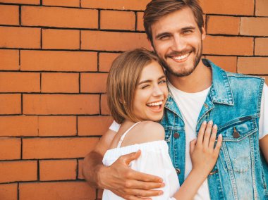 Gülümseyen güzel kız ve onun yakışıklı erkek arkadaşı. Rahat yazlık elbiseli kadın. Kot pantolon giyen adam. Mutlu neşeli bir aile. Kadın tuğla duvara yakın sokakta eğleniyor. Sarılan çift 