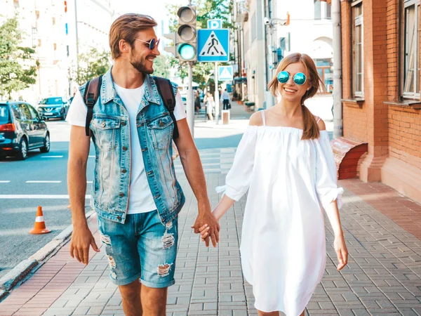 Gülümseyen güzel kız ve yakışıklı erkek arkadaşı. Gündelik yazlık elbiseli kadın ve kot elbiseli adam. Mutlu, neşeli bir aile. Kadın arka planda eğleniyor. Güneş gözlüklü çifte sarılıyor.