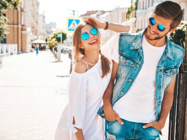 Gülümseyen güzel kız ve onun yakışıklı erkek arkadaşı sokakta poz. Rahat yazlık elbiseli kadın ve kot pantolon giyen bir erkek. Mutlu neşeli çift aile güneş gözlüğü eğlenmek
