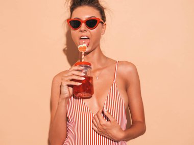 Güneş gözlüğü genç güzel seksi gülümseyen hipster kadın. Yazlık mayo giyen kız. Bej duvar yakınında poz, taze kokteyl smoozy içecek içme