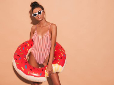 Güneş gözlüğü genç güzel seksi gülümseyen hipster kadın. Donut lilo şişme yatak ile yaz mayo mayo Kız. Pozitif kadın deliriyordu. Bej duvarın yakınında poz vermek