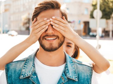 Gülümseyen güzel kız ve onun yakışıklı hipster erkek arkadaşı. Kadın erkek gözlerini elleriyle kapatıyor. Mutlu neşeli bir aile. Dışarıda duran sevgi dolu çifte sarılıyorlar. Bil bakalım kim kavramı 